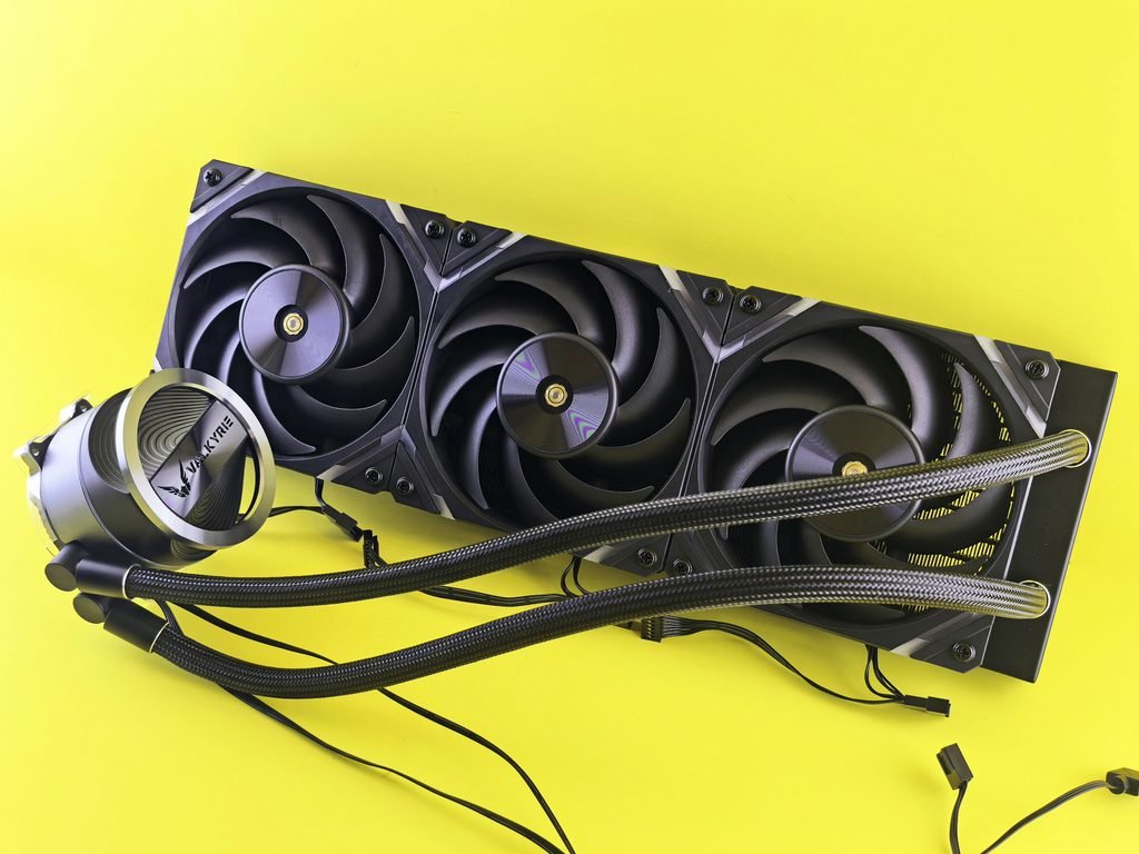 Water cooler de 360mm, com três ventoinhas, radiador e bloco de água conectados por mangueiras, sobre fundo amarelo